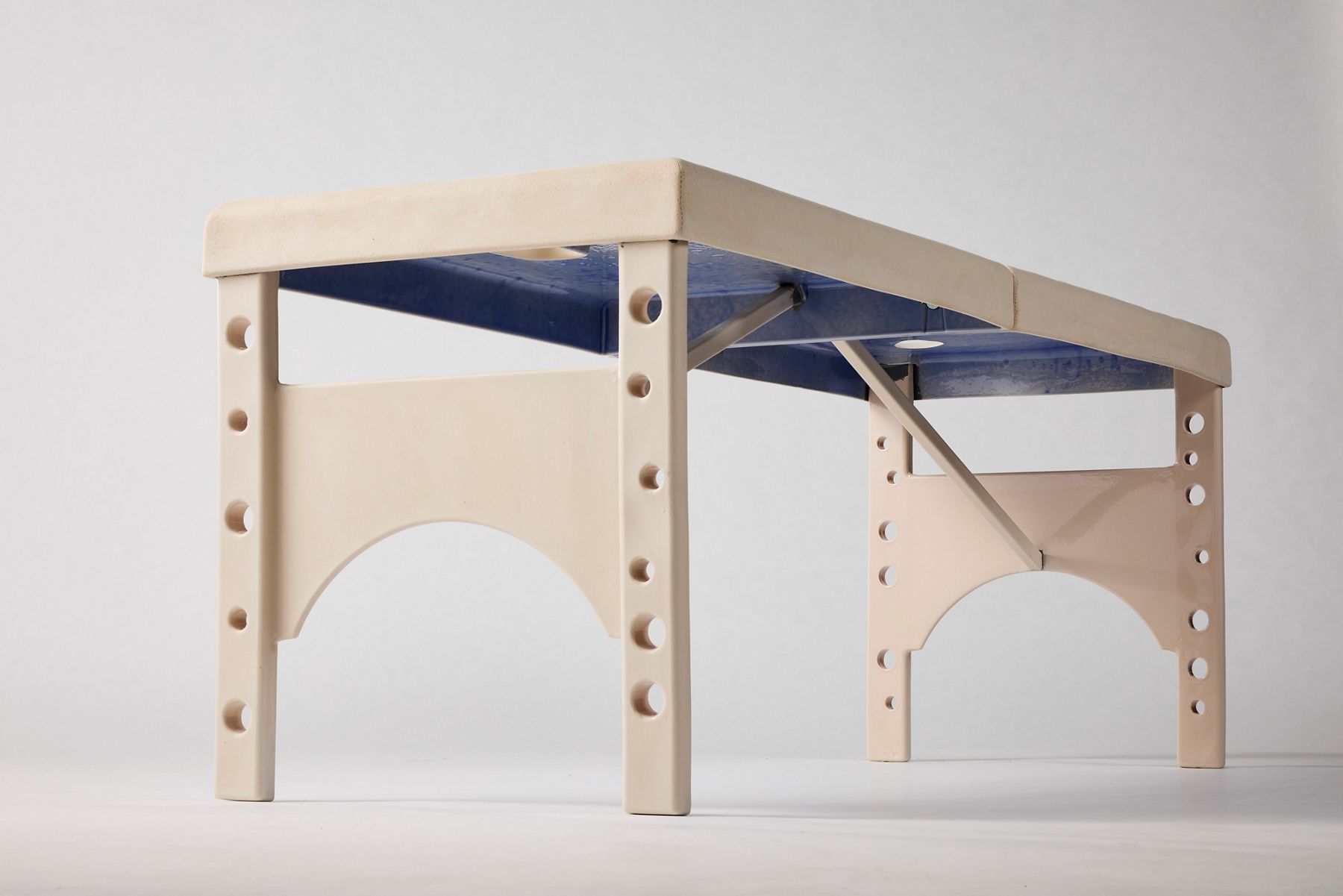 Minimalist handcrafted bench-like sculpture made from light wood with rounded edges, exposed peg joinery, arched cutout legs, and a blue underside panel. Kohler MakerSpace resident Patty Chang’s Abyssal explored themes of identity, labor, and societal expectations, and was exhibited at The Metropolitan Museum of Art in New York in 2025.