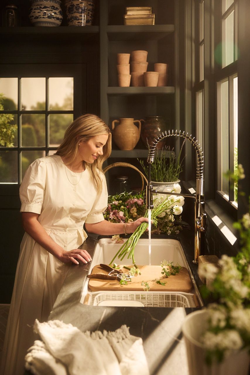 Farmhouse kitchen sink installed with Shea McGee preparing food at the sink under natural light.