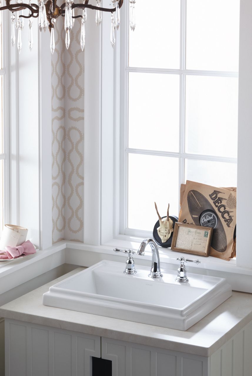 A white rectangular sink with deck mount faucet and a decorative ledge around its exterior.