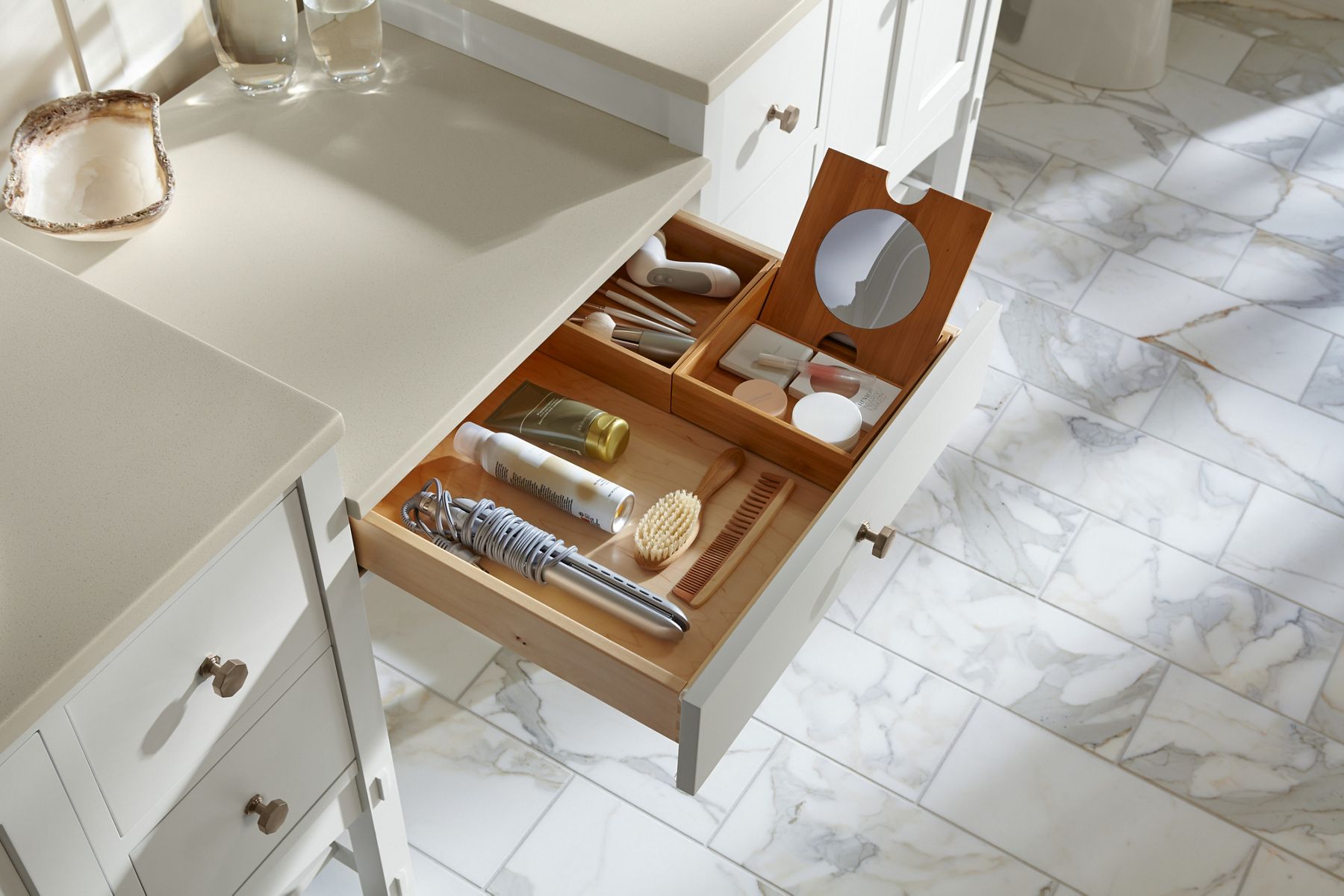 The open drawer of a bathroom vanity showing organizational dividers with a range of bahtrooom products.