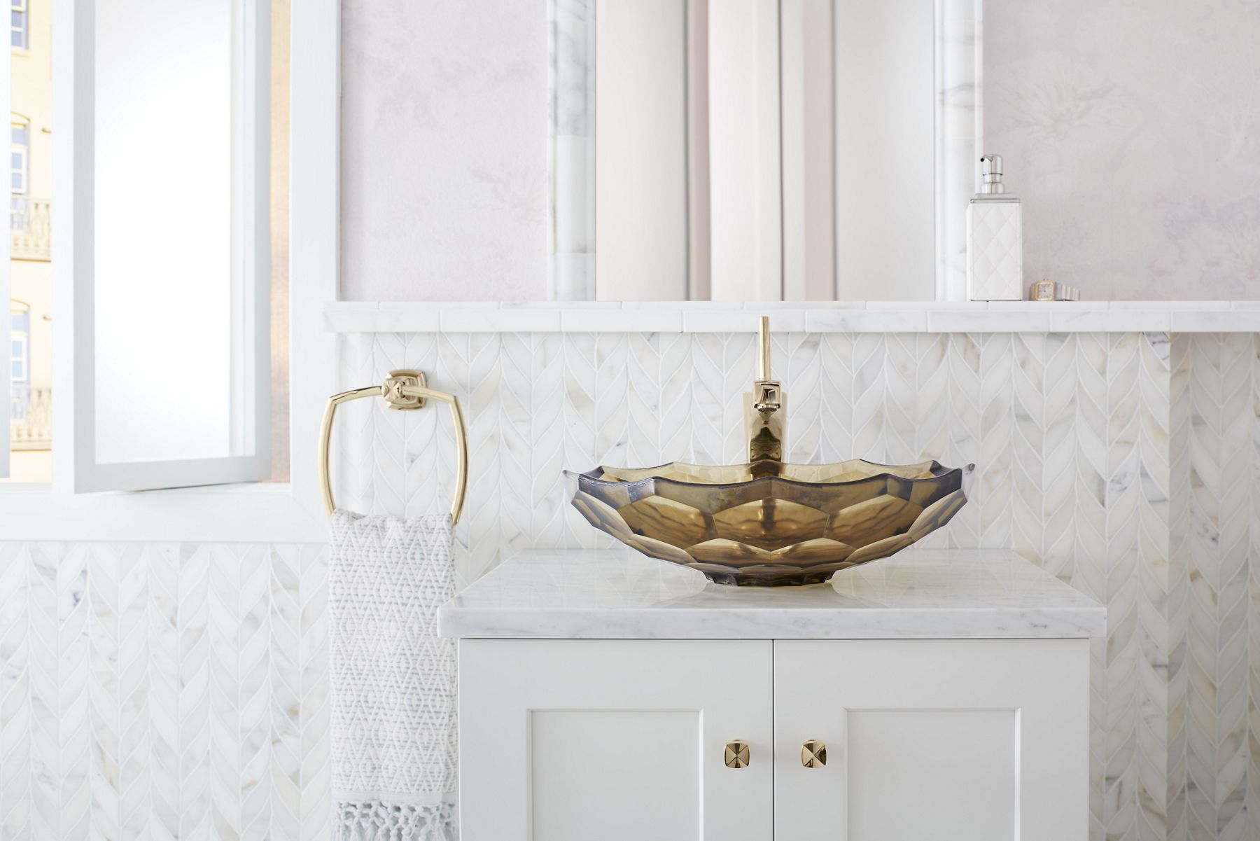 Daylight in bright, white-toned bathroom with open window overlooking a cityscape featuring a white bathroom vanity with Vibrant French Gold cabinet hardware and Briolette glass vessel sink and Margaux faucet.