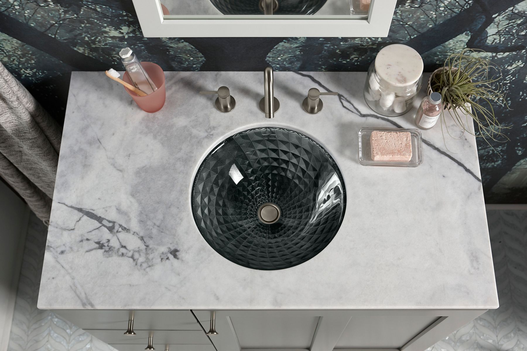 A undermount greenish gray sink with square shapes in a circular pattern around its interior.