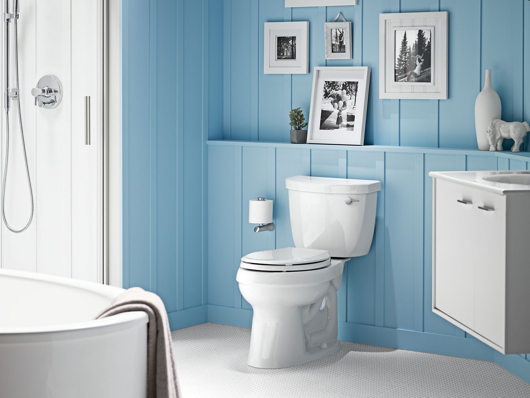 Une salle de bain avec des murs turquoise, une toilette blanche Corbelle de KOHLER et un meuble-lavabo mural blanc.