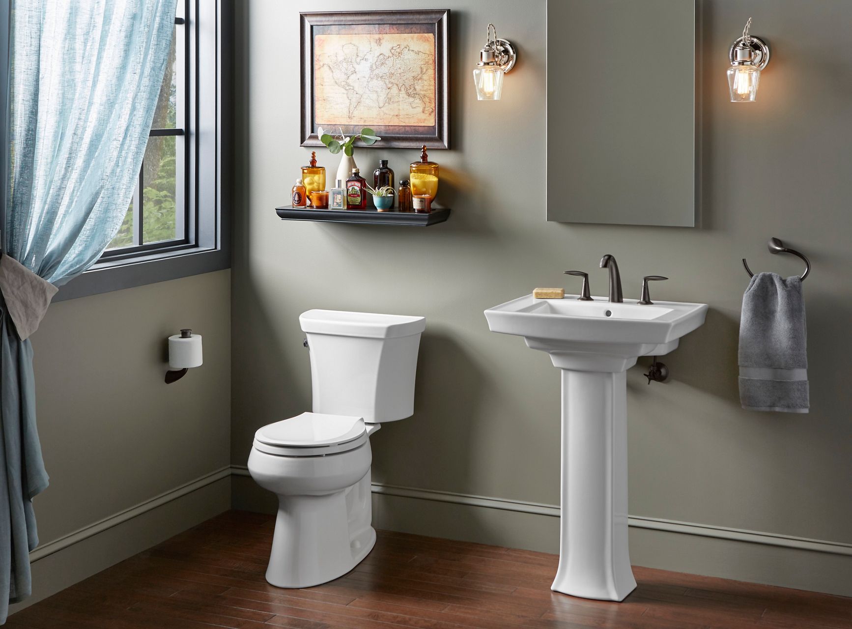 A pedestal sink against a neutral green wall.