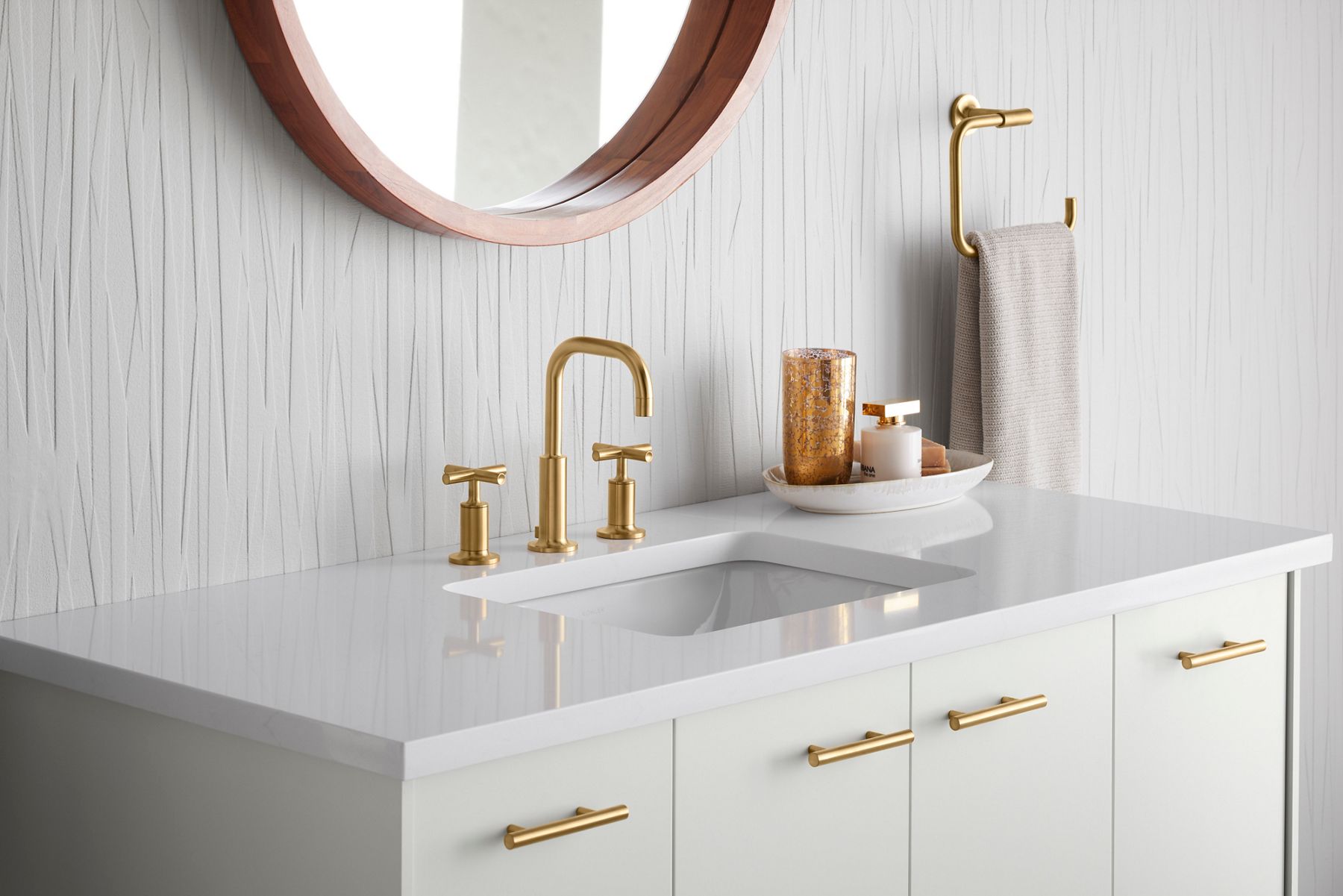 A white vanity and counter top with a brushed brass contemporary faucet and hardware.