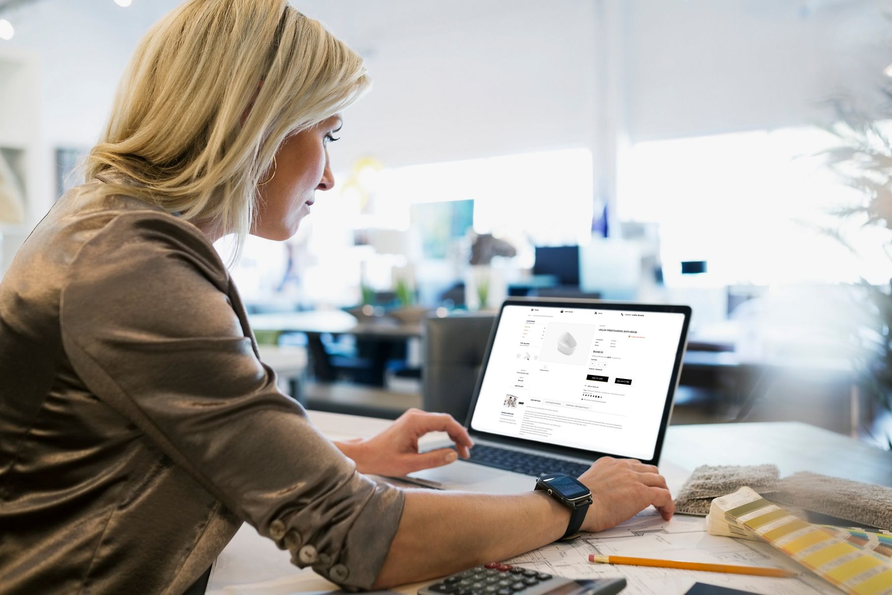 Two hands operating a laptop computer in an office environment.