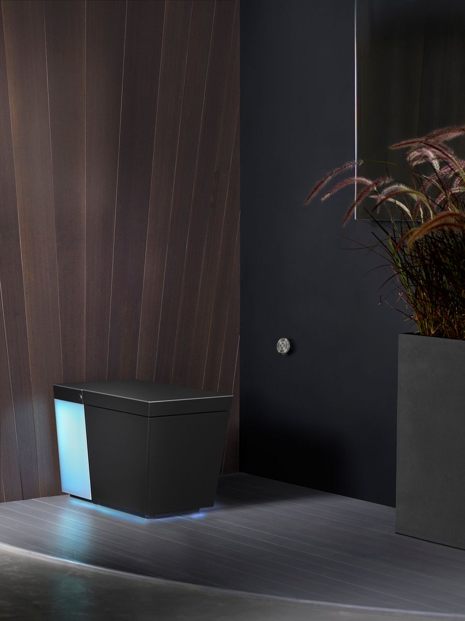 A Numi 2.0 toilet in a darkened bathroom with the rear illuminated in a blue light.