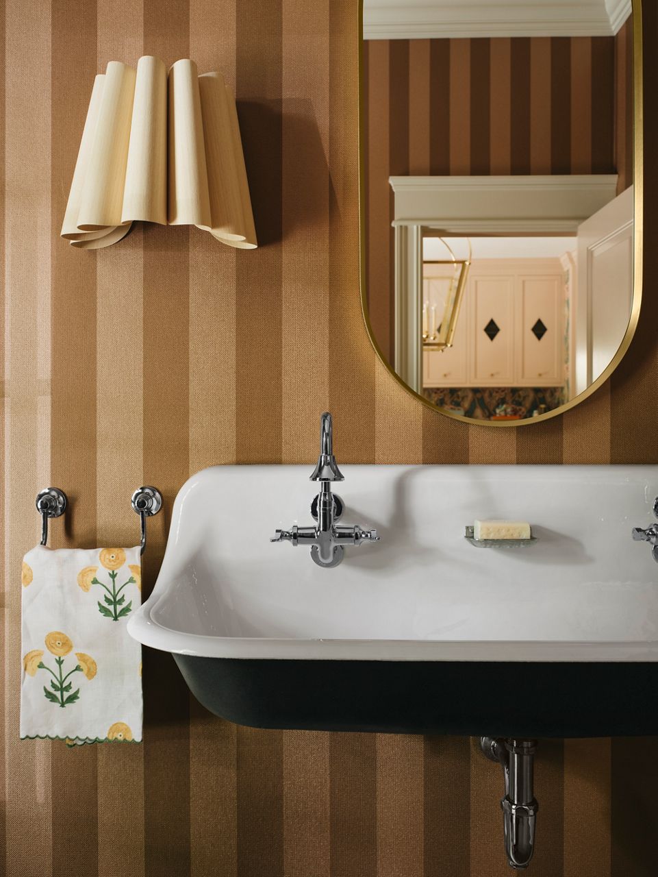 Vintage-inspired polished silver faucet and soap dish attached to a wall-mount utility sink.