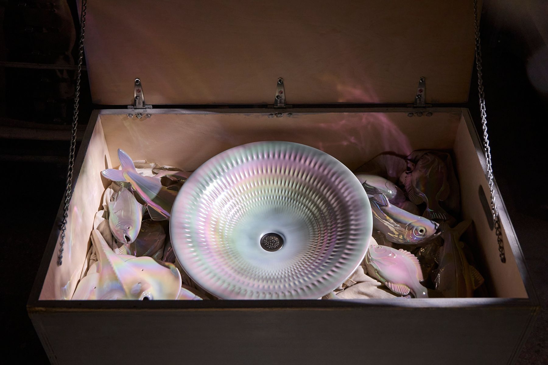 Artistic, multicolored sink nestled into a bed of fish figurines.