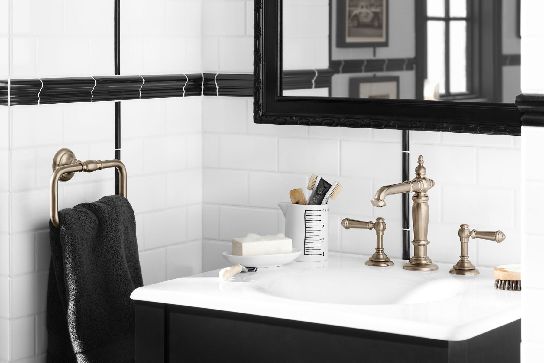 Black and white bathroom with white subway tile and black accents featuring black vanity with white sink and Artifacts bathroom faucet and accessories in Vibrant Brushed Bronze.