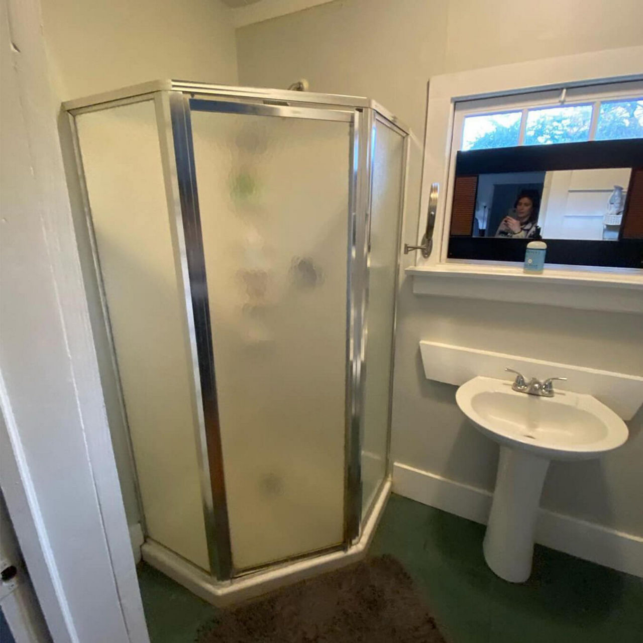 An after picture of @demiliodesign's pink renovated bathroom including a hinge-door pentagon shower enclosure with geometric green tiles.