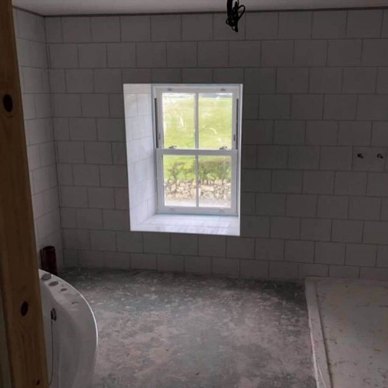 A before picture of @shelley_clegirfarm's unfinished bathroom with a large window.