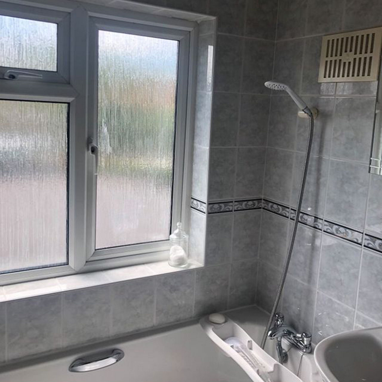 A before picture of @1930s_solo_renovation's shower over bath area with grey and ornamental tiles.