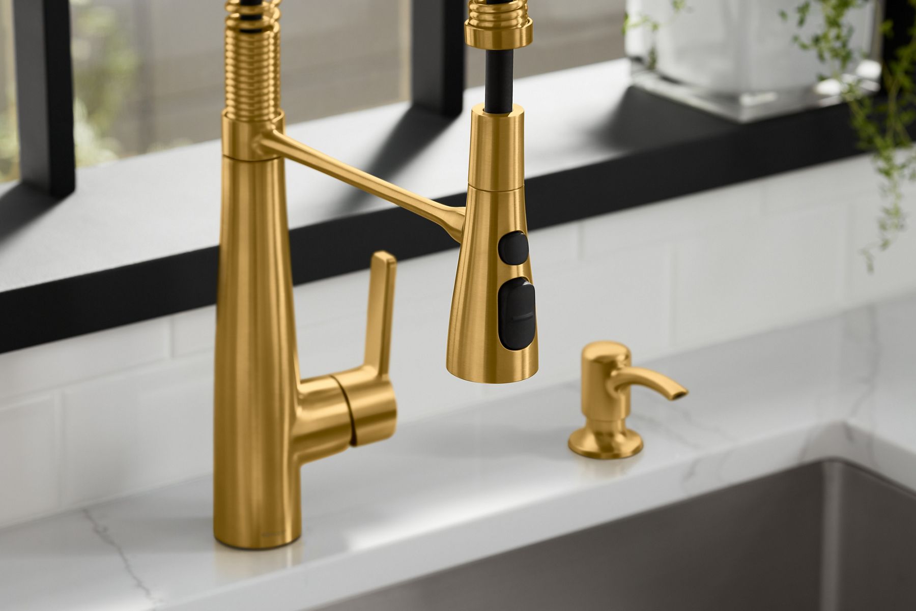 A close up shot of a gold sink faucet with black buttons.