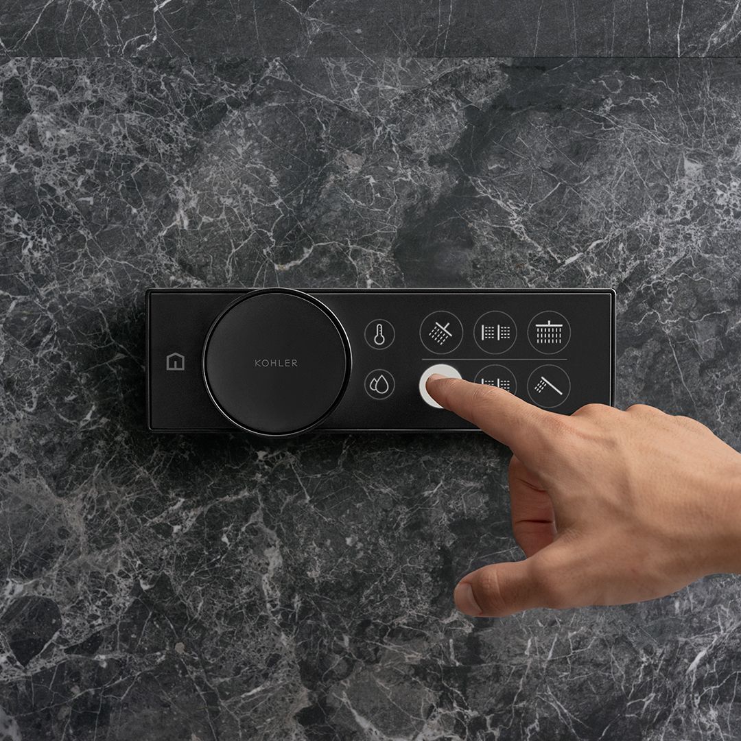Close-up detail of a hand touching a button on a black digital shower control.
