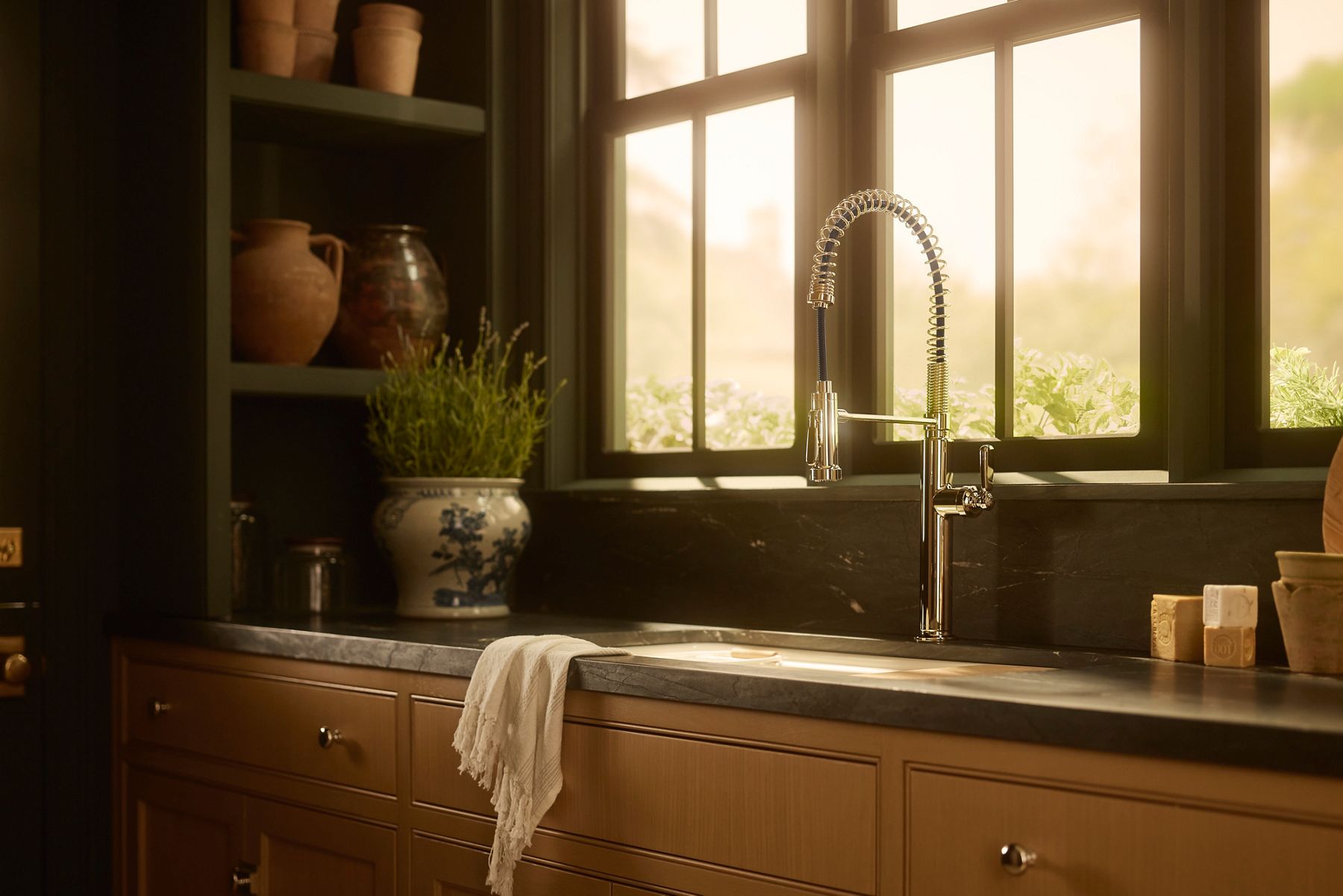 The Audrine kitchen sink with an arched silver faucet next to a window.
