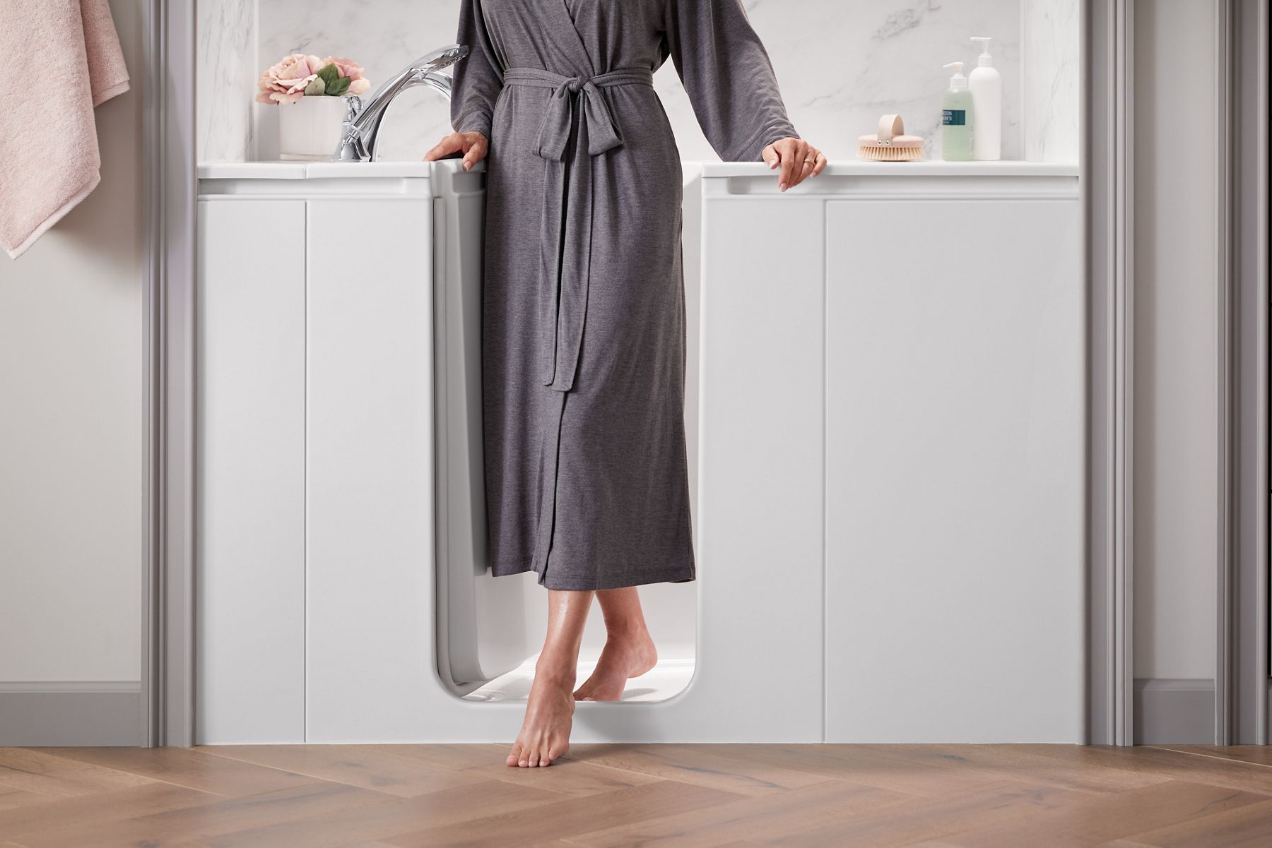 Person standing barefoot on a tiled bathroom floor wearing a robe.