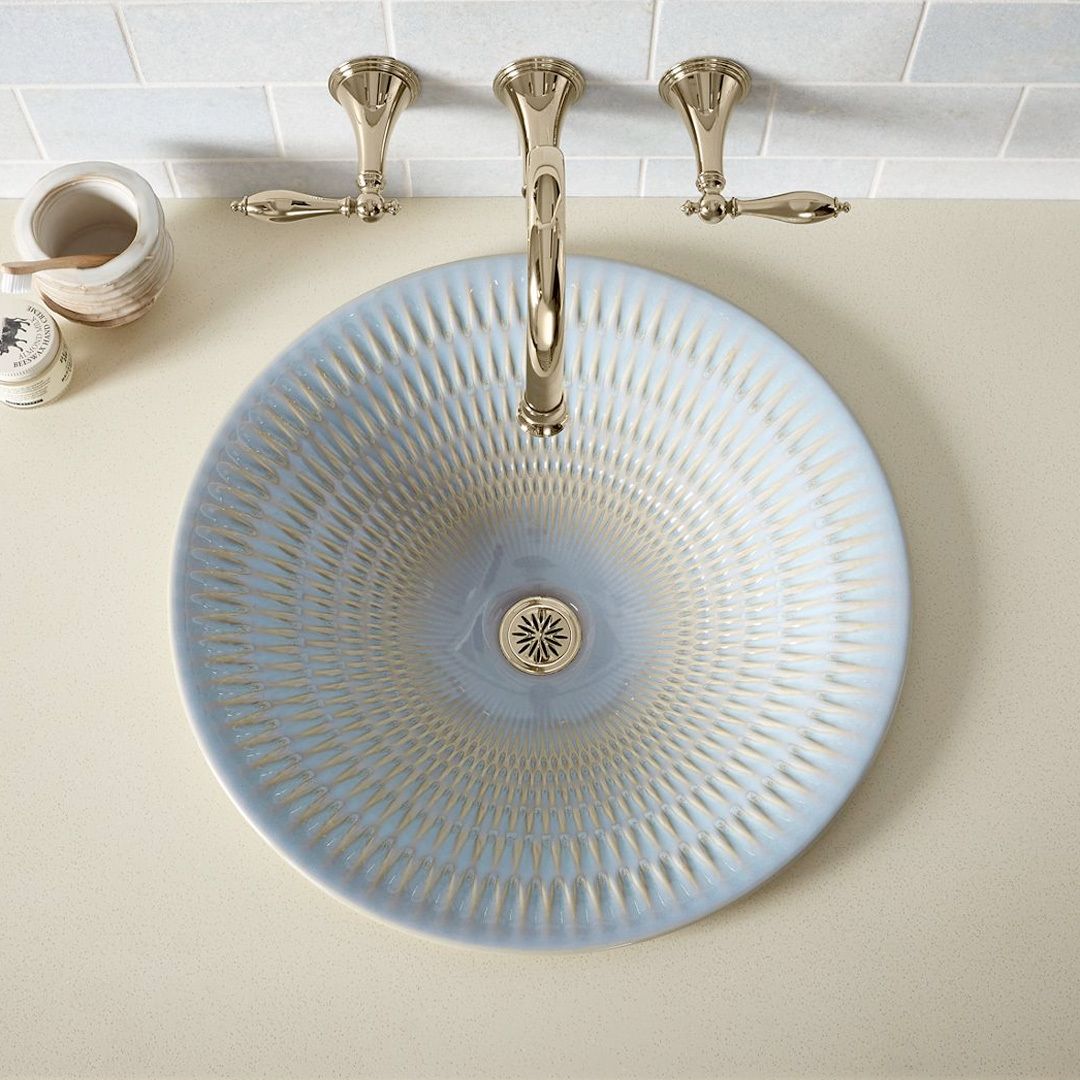 Top view of white glazed cermaic vessel sink with hand-carved pattern and faucet.