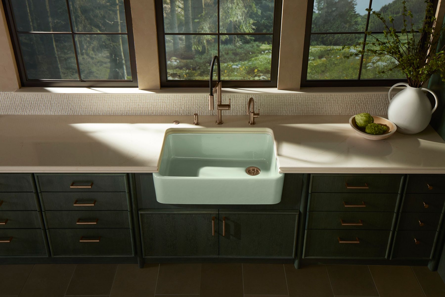 White farmhouse-style kitchen sink with black faucet, placed in a natural light setting.