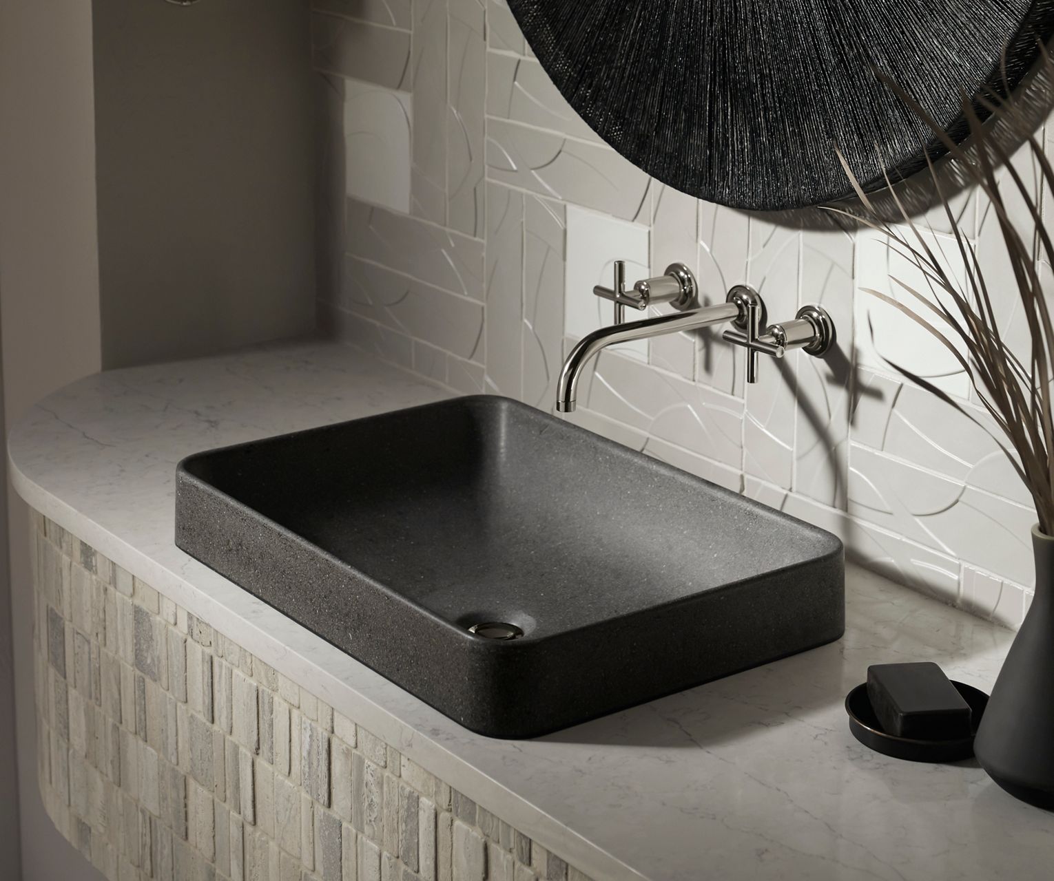 Bathroom sink with a black rectangular design and wall-mounted faucet, displayed against white textured tile.