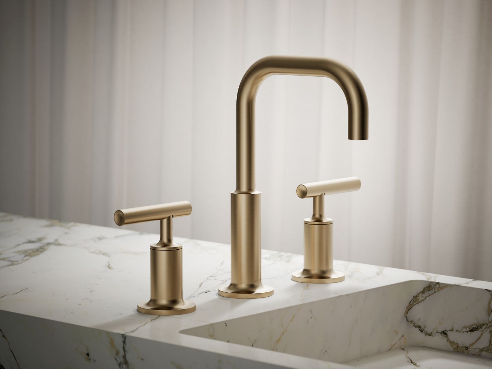 Close-up of a brushed gold bathroom faucet set over a white sink.