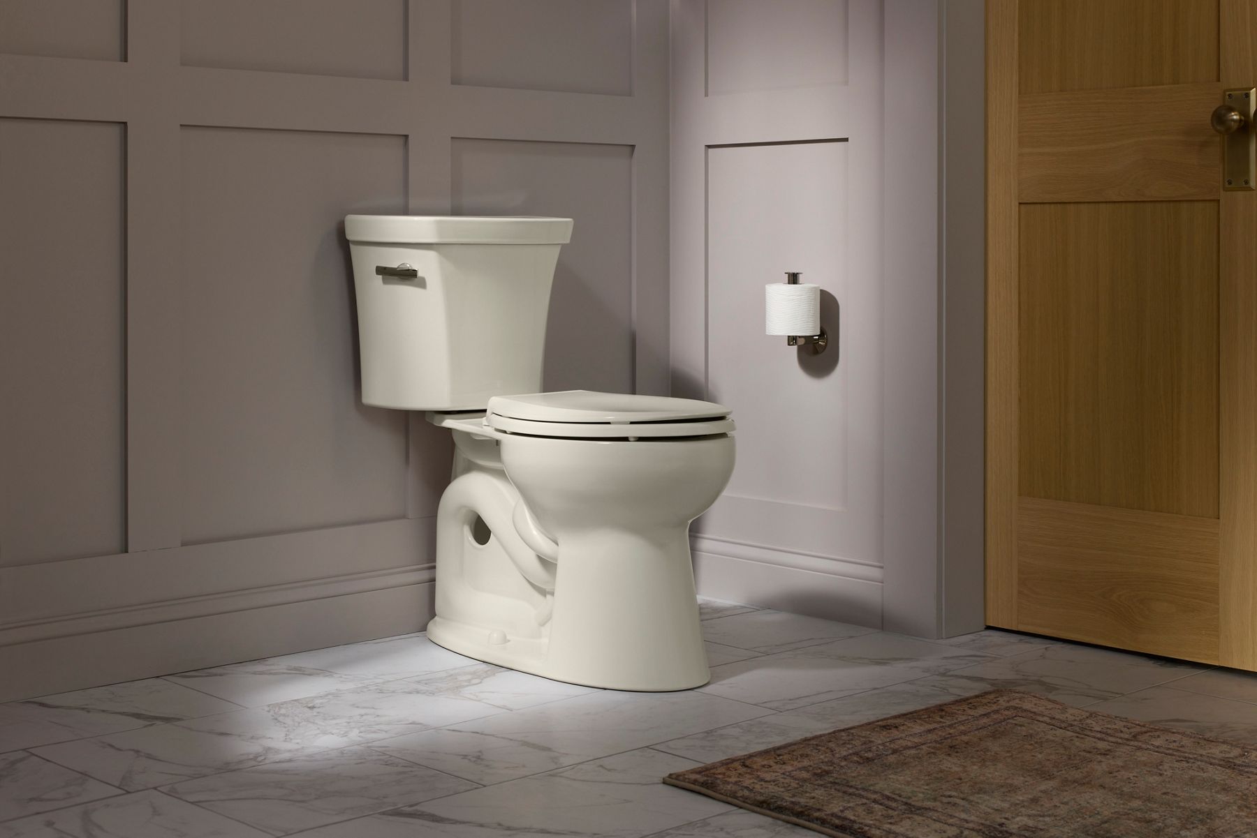Two-piece white toilet with separate tank and bowl in bathroom with light walls.