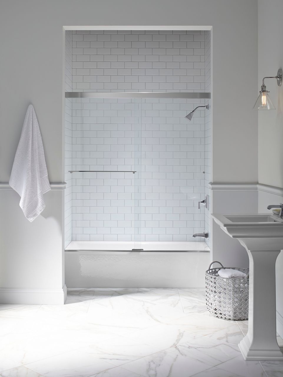 A white alcove baththub and white tile shower with shower head, faucet, and lever and sliding glass shower door