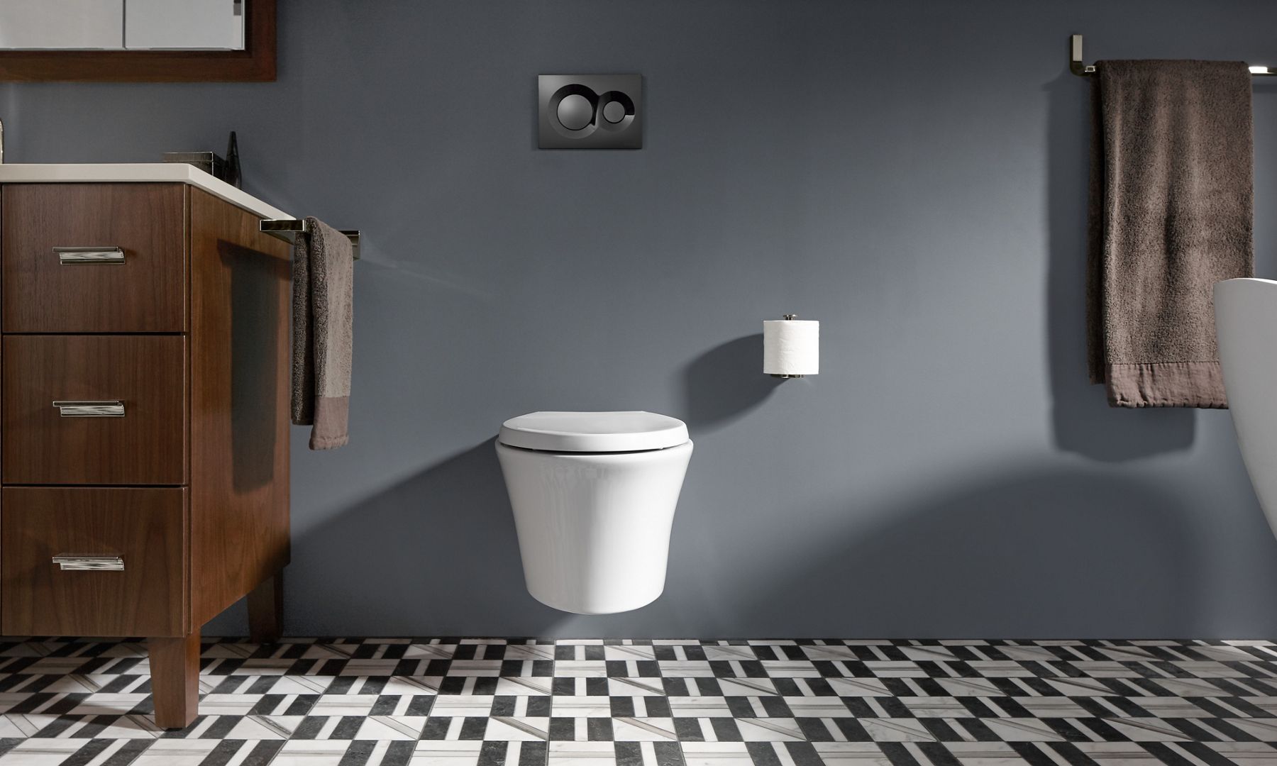 A white wall-mount toilet on a gray wall with geometric tile below.