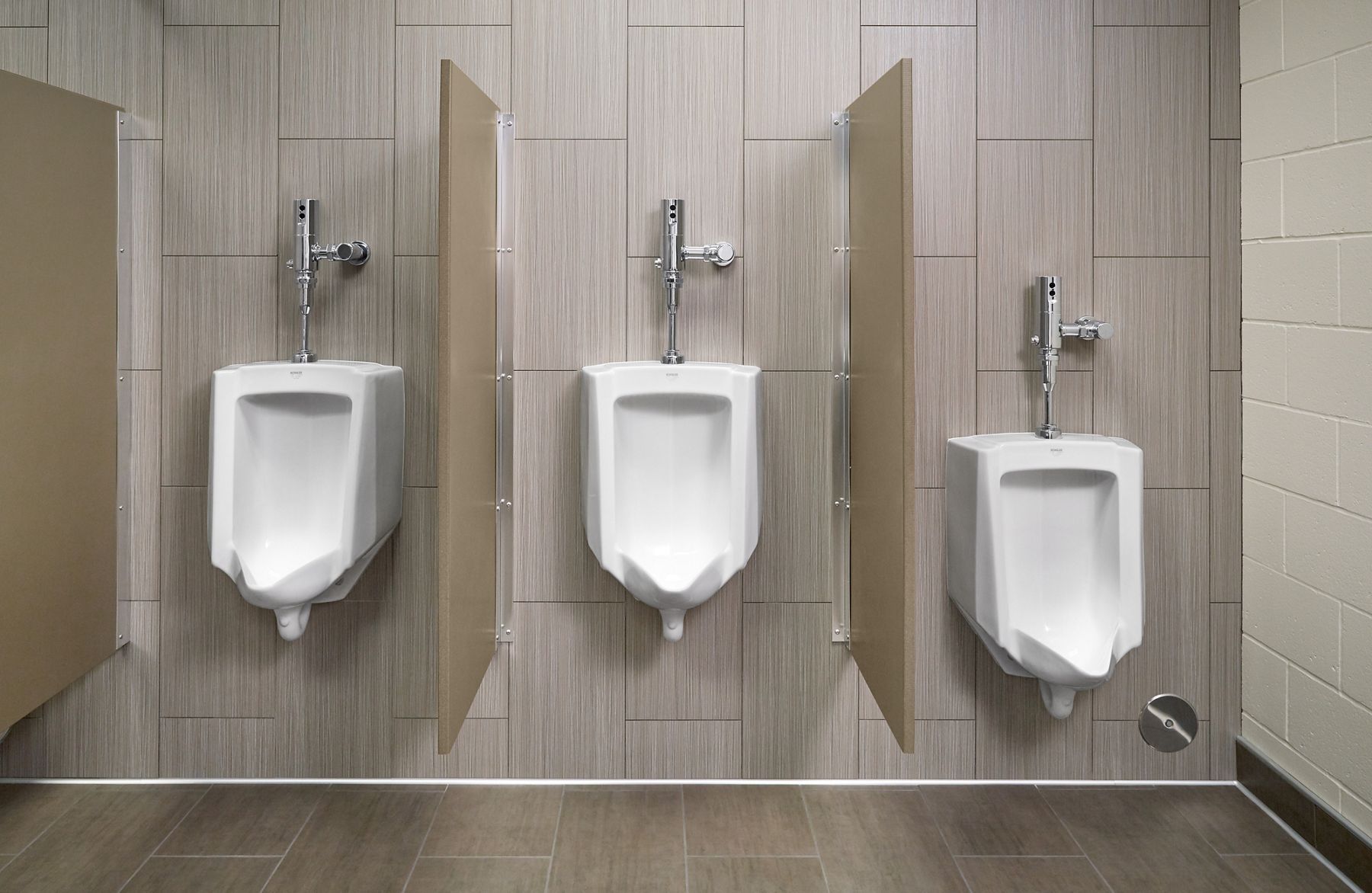 A urinal on a cream-colored tile wall.