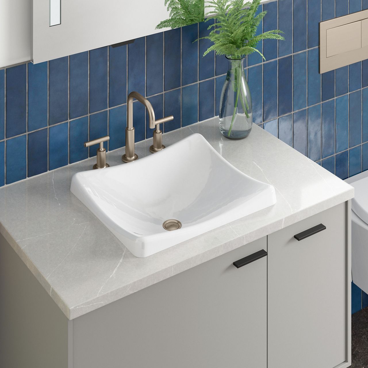 A white sink on a light gray counter top with a polished nickel faucet and blue tile wall.