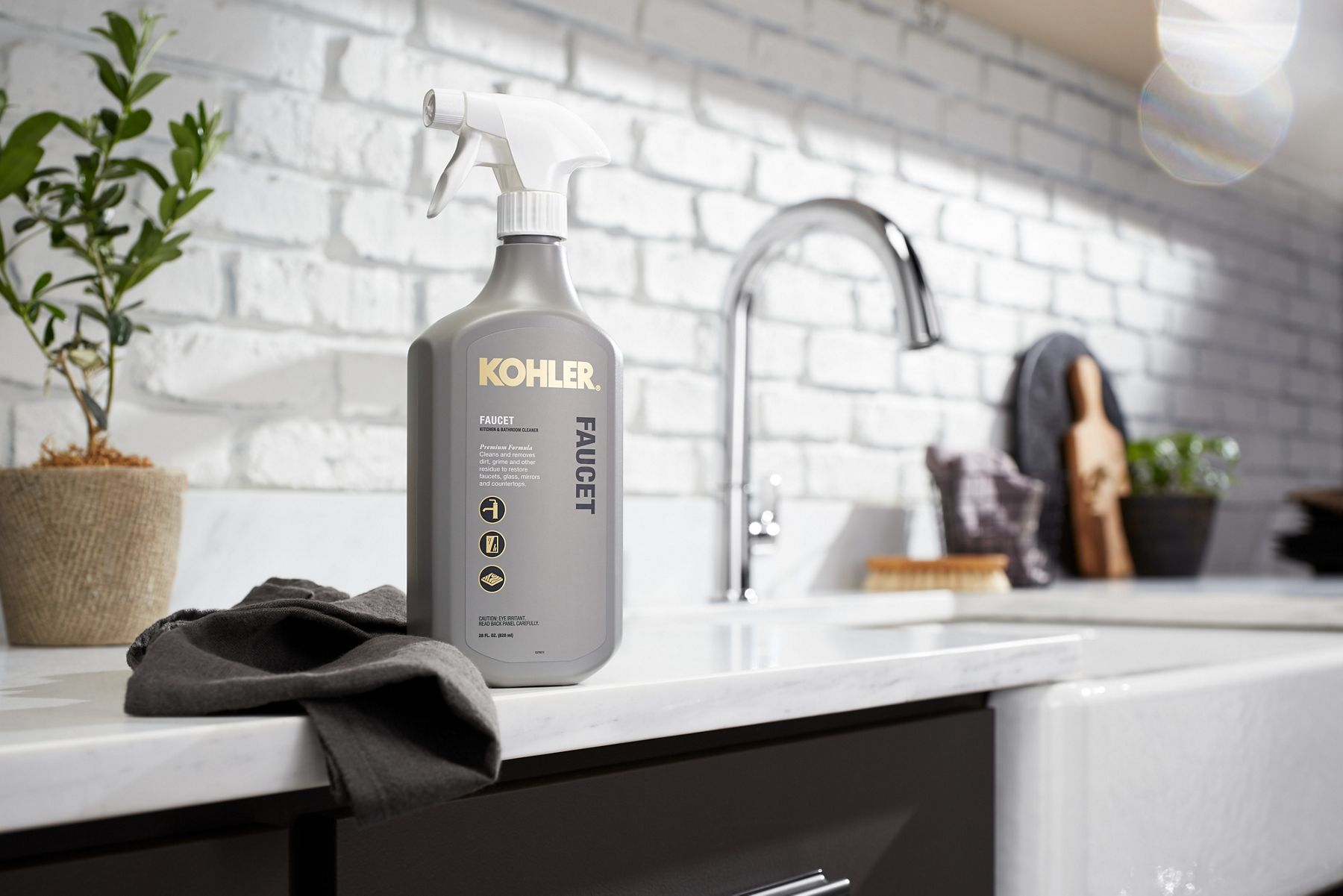 A bottle of faucet cleaner sitting on a counter top in front of a white painted brick wall.