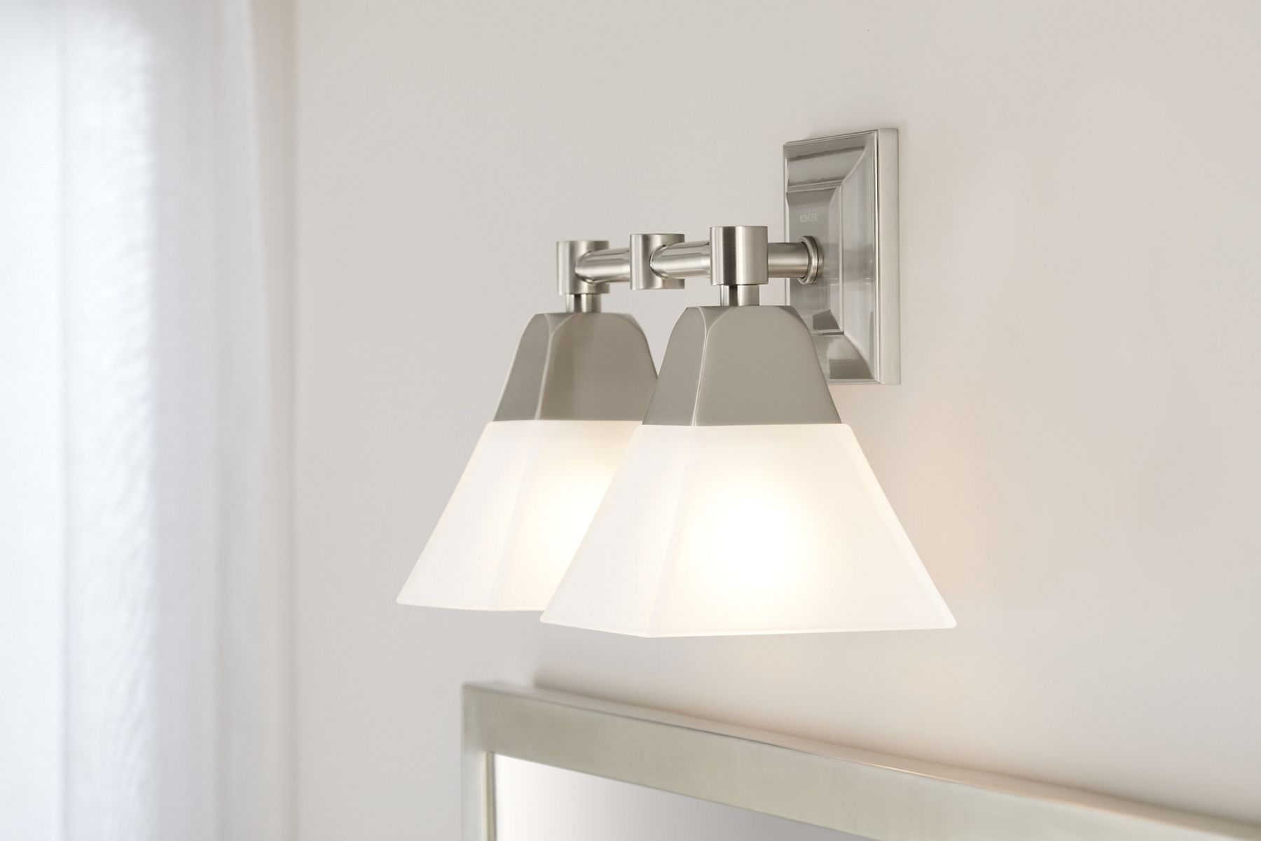 Light, white and cream bathroom with Kohler Memoirs three-light, polished chrome sconce over white mirror and coordinating vanity