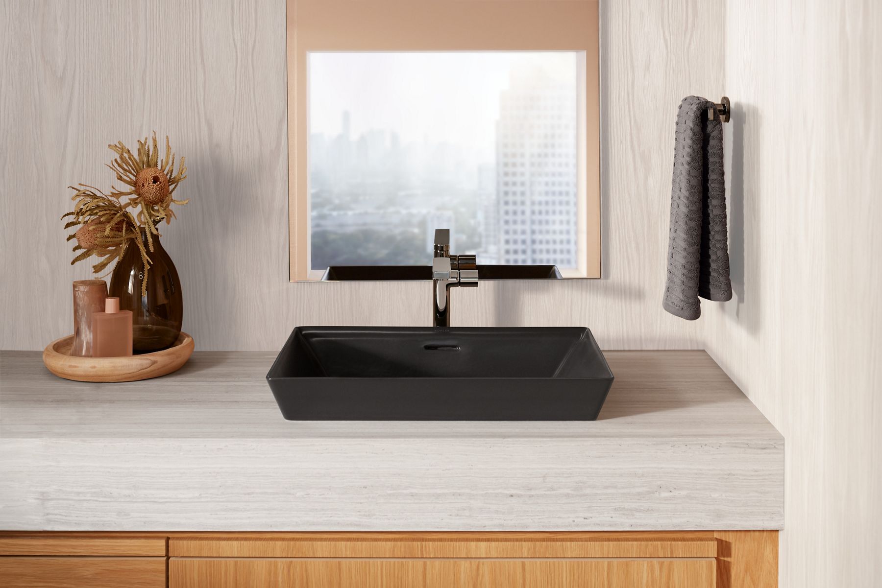 Front view of a black Brazn sink on a cream-colored vanity with a titanium-finished contemporary faucet.