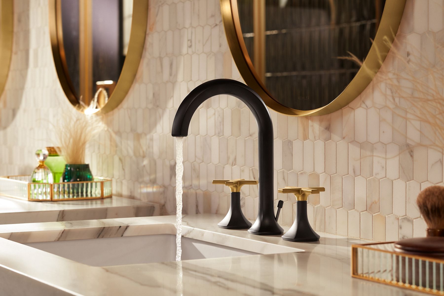 A two tone faucet pouring water into a white undermount sink in a bathroom with cream colored walls.