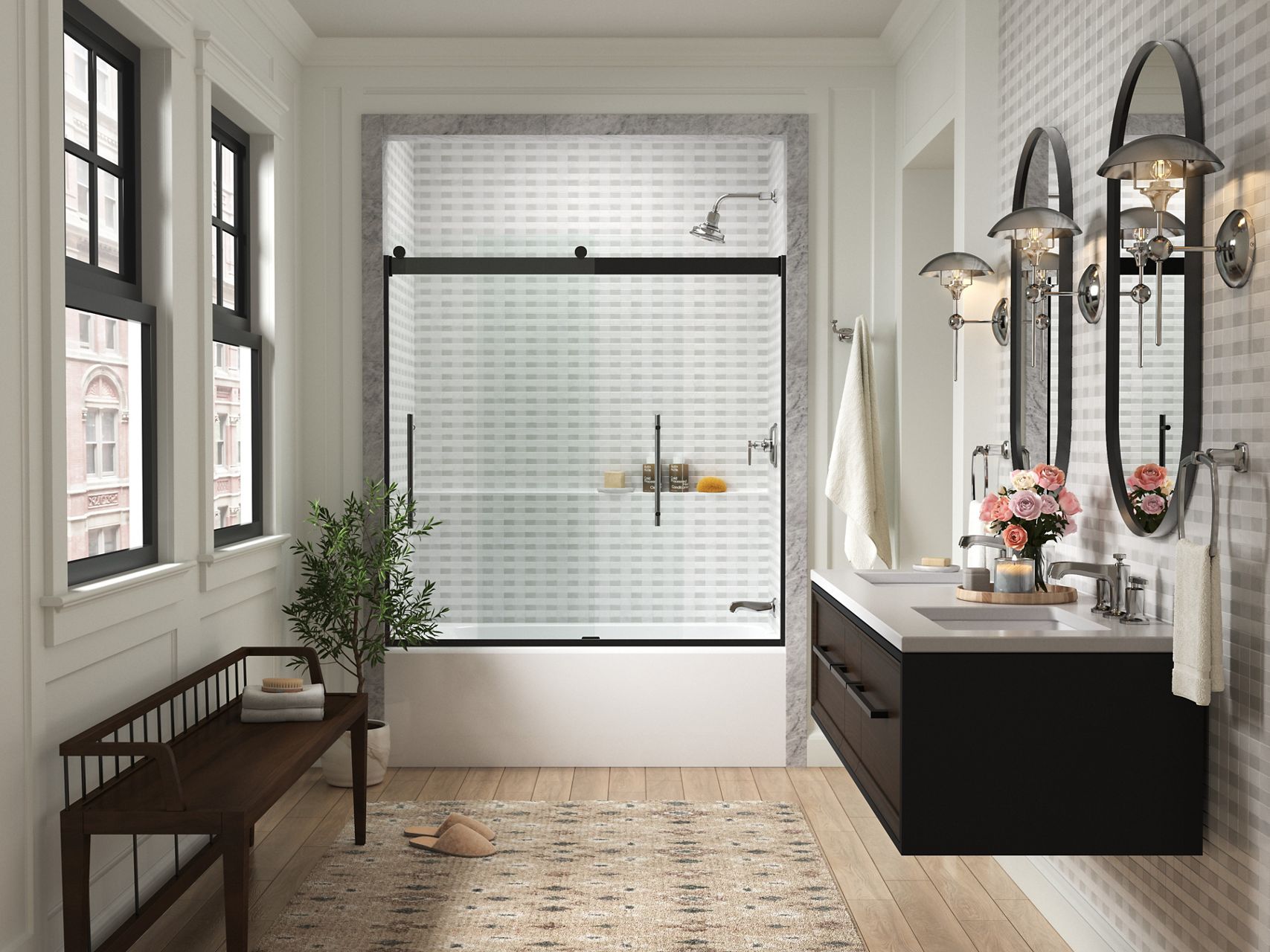 KOHLER glass sliding shower doors at the end of a white bathroom with two windows and a black bench on one side and two oval mirrors with black wall-mounted vanity on the other side.