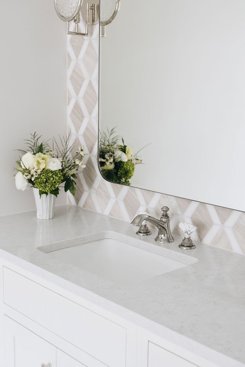Side view of a white Caxton undermount sink in a white counter top with a polished chrome faucet.