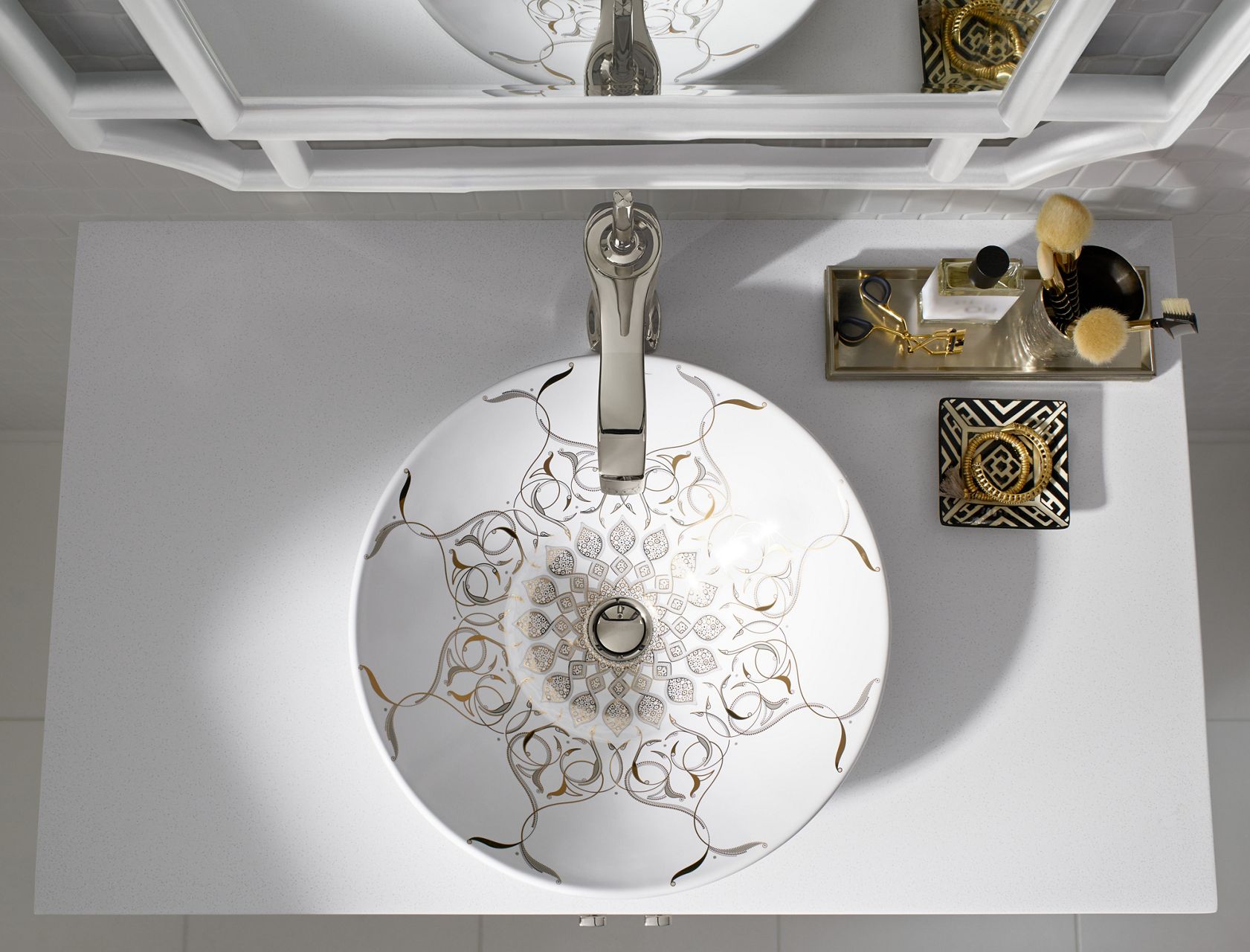 Overhead view of a round white sink with ornate gold patterning.