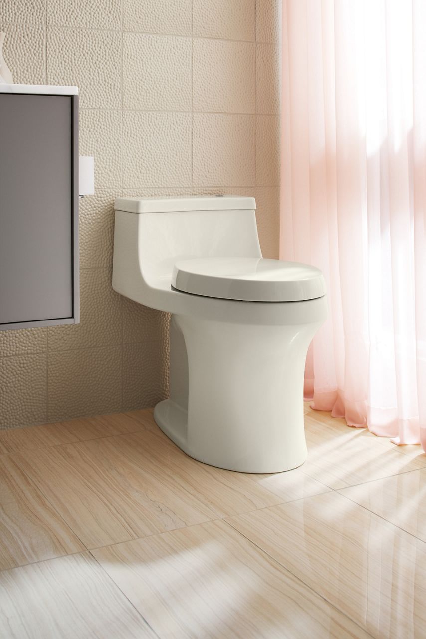 A white one-piece toilet in a bathroom with pink curtains and tan walls.