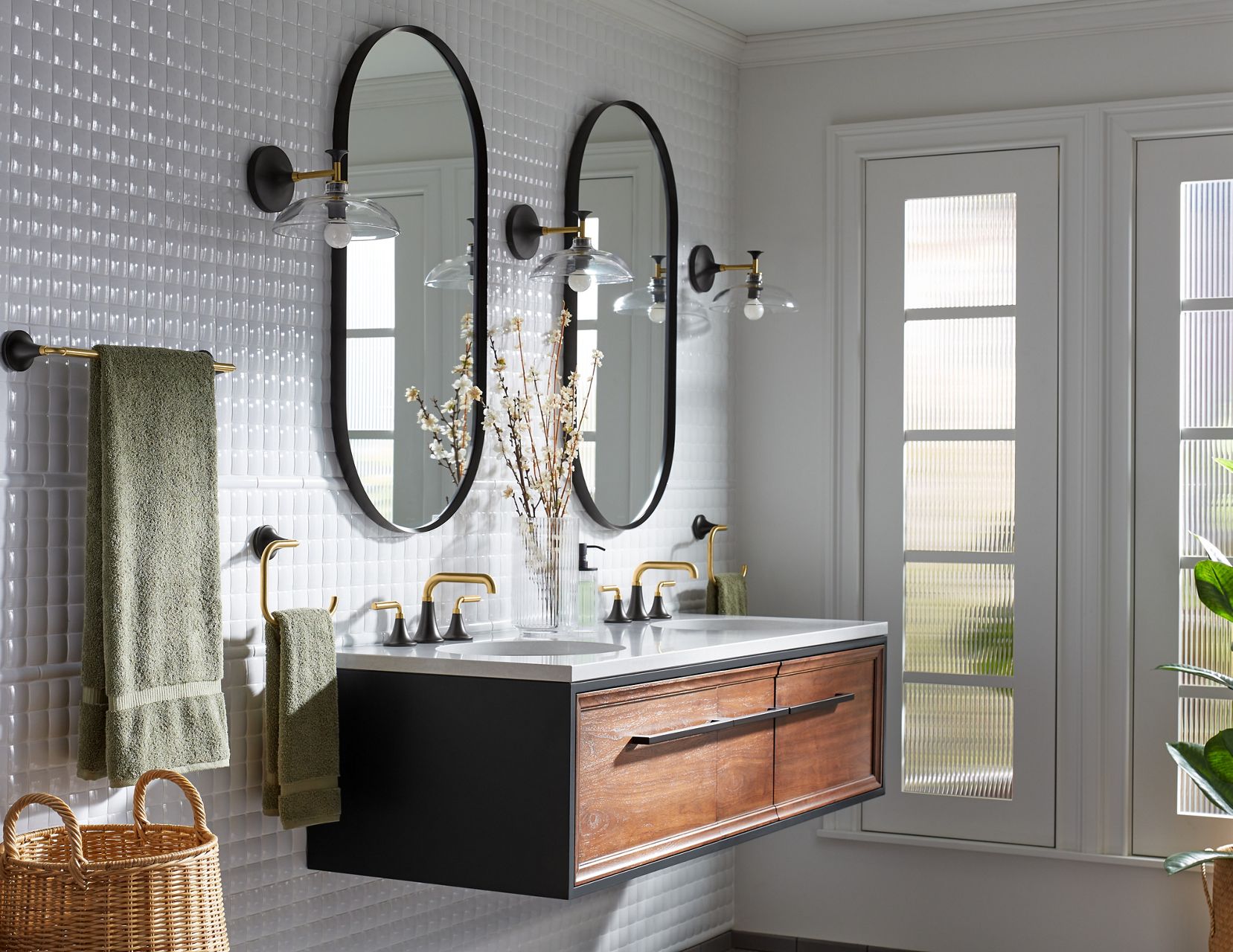 Des accessoires de salle de bain KOHLER, tels que les récipients à savon et les bougies, sont disposés sur une table en bois avec des rubans, comme s’il s’agissait d’un panier cadeau.