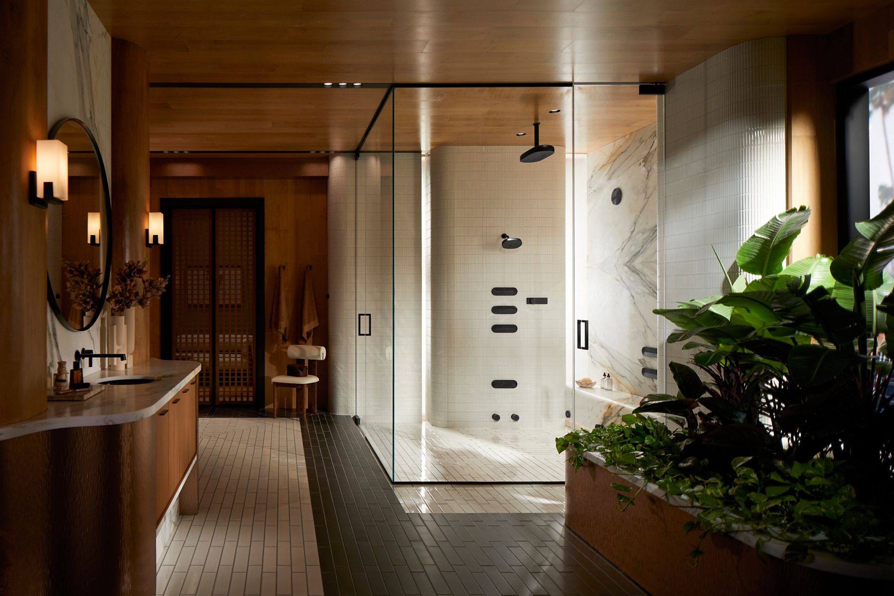 Modern glass-enclosed shower with chrome rainfall showerhead and handheld sprayer.