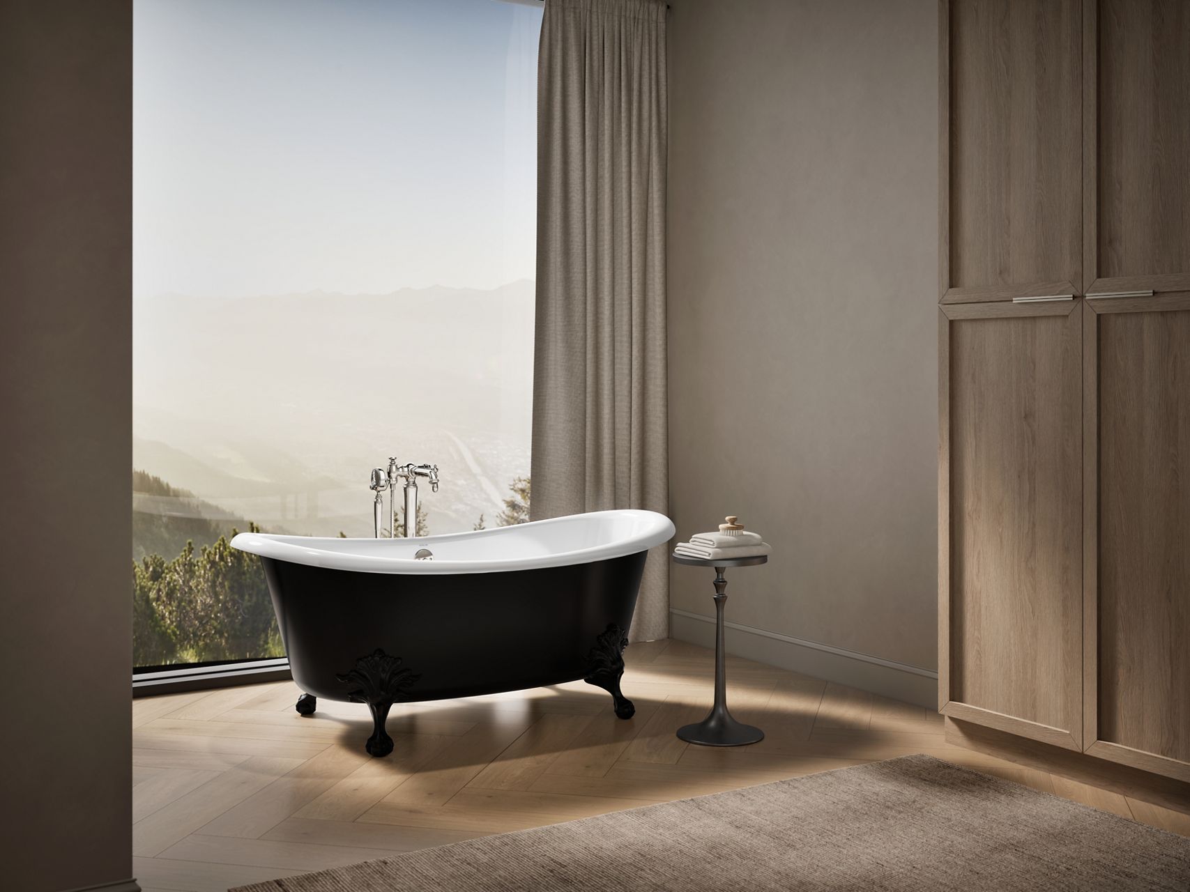 Freestanding black clawfoot bathtub in a modern bathroom with large windows and mountain view.
