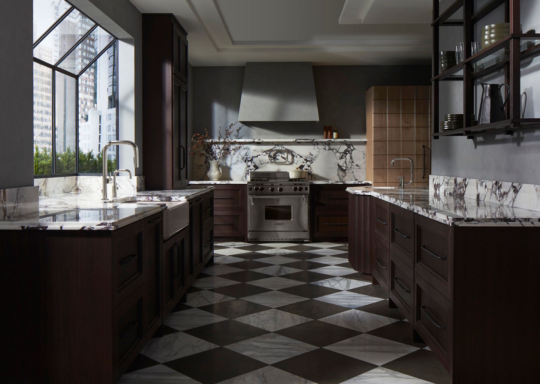 A kitchen with checkered floors and dark wood cabinets with marbled white and gray counter tops and back splashes on the left, right, and center background of the image.