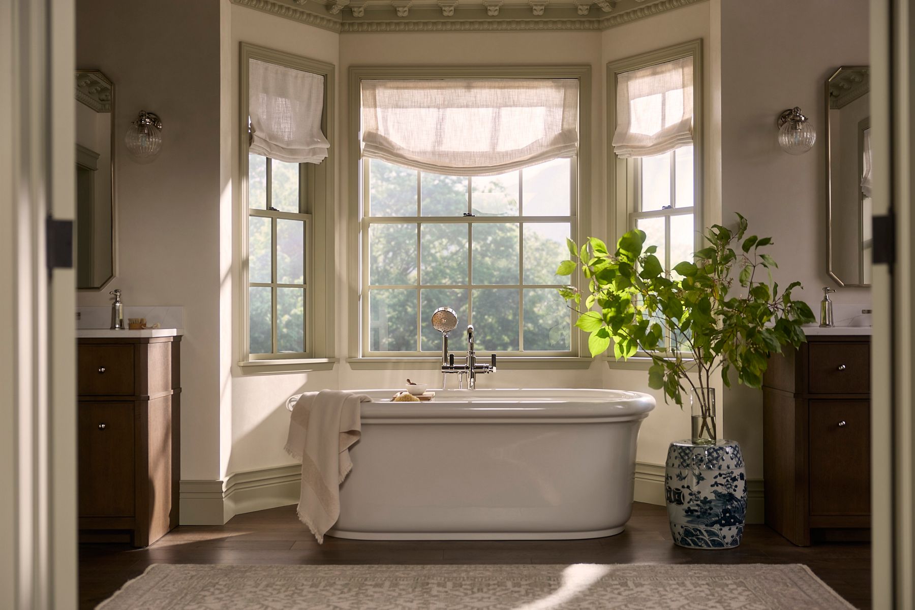 Wide bathroom view with a central freestanding bathtub, large windows, and natural light filling the space