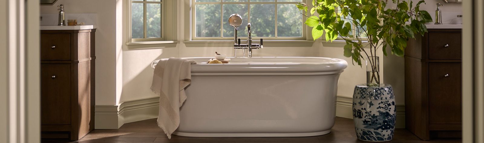 Wide bathroom view with a central freestanding bathtub, large windows, and natural light filling the space