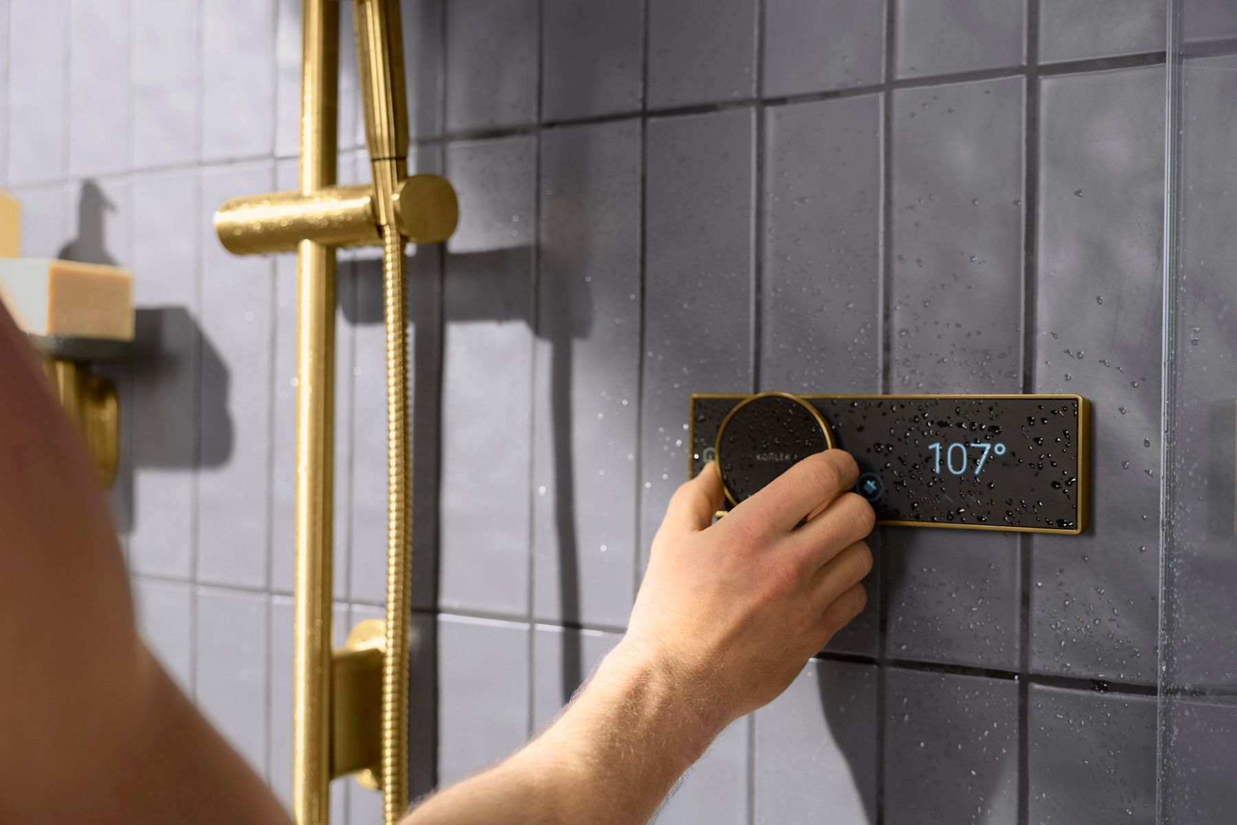 Hand adjusting the Kohler Anthem EvoCycle digital shower controller displaying the water temperature.