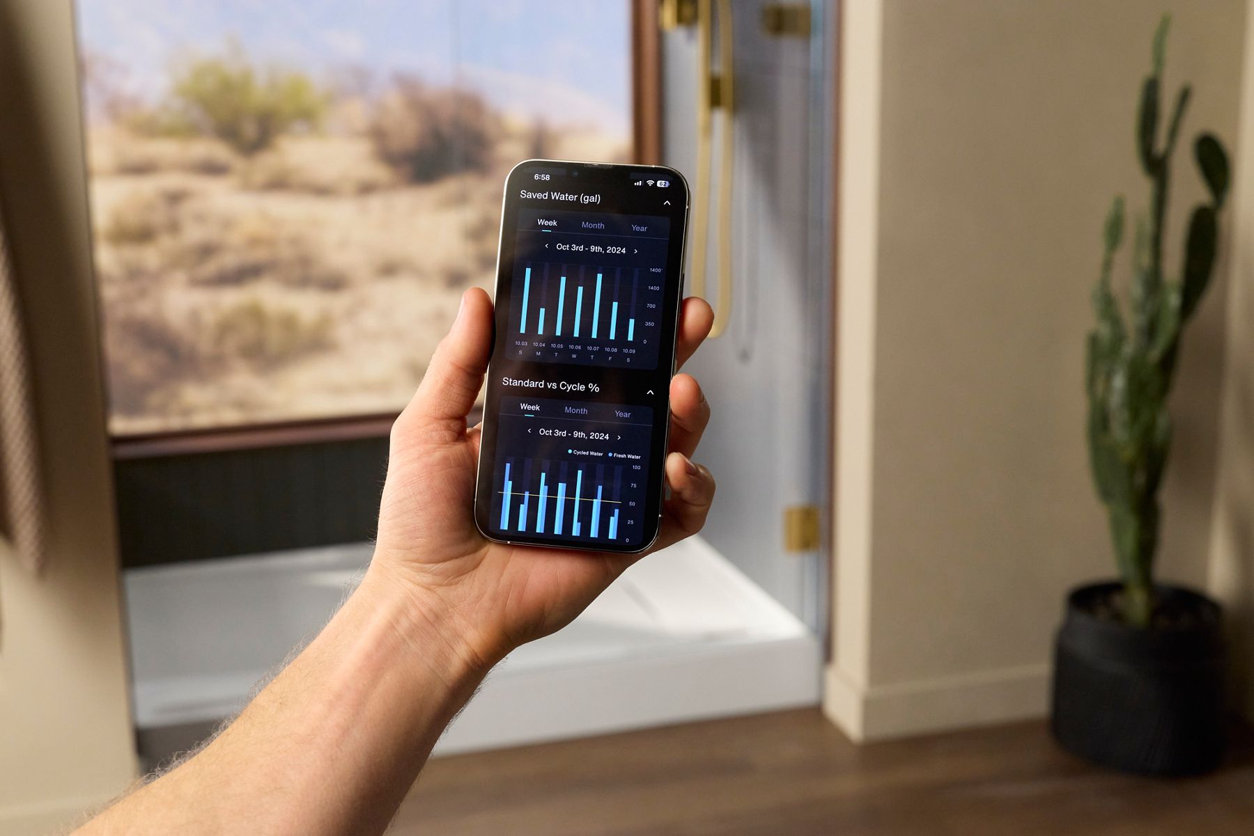 Hand holding a smartphone displaying the Kohler Konnect app with water usage insights and shower performance data.
