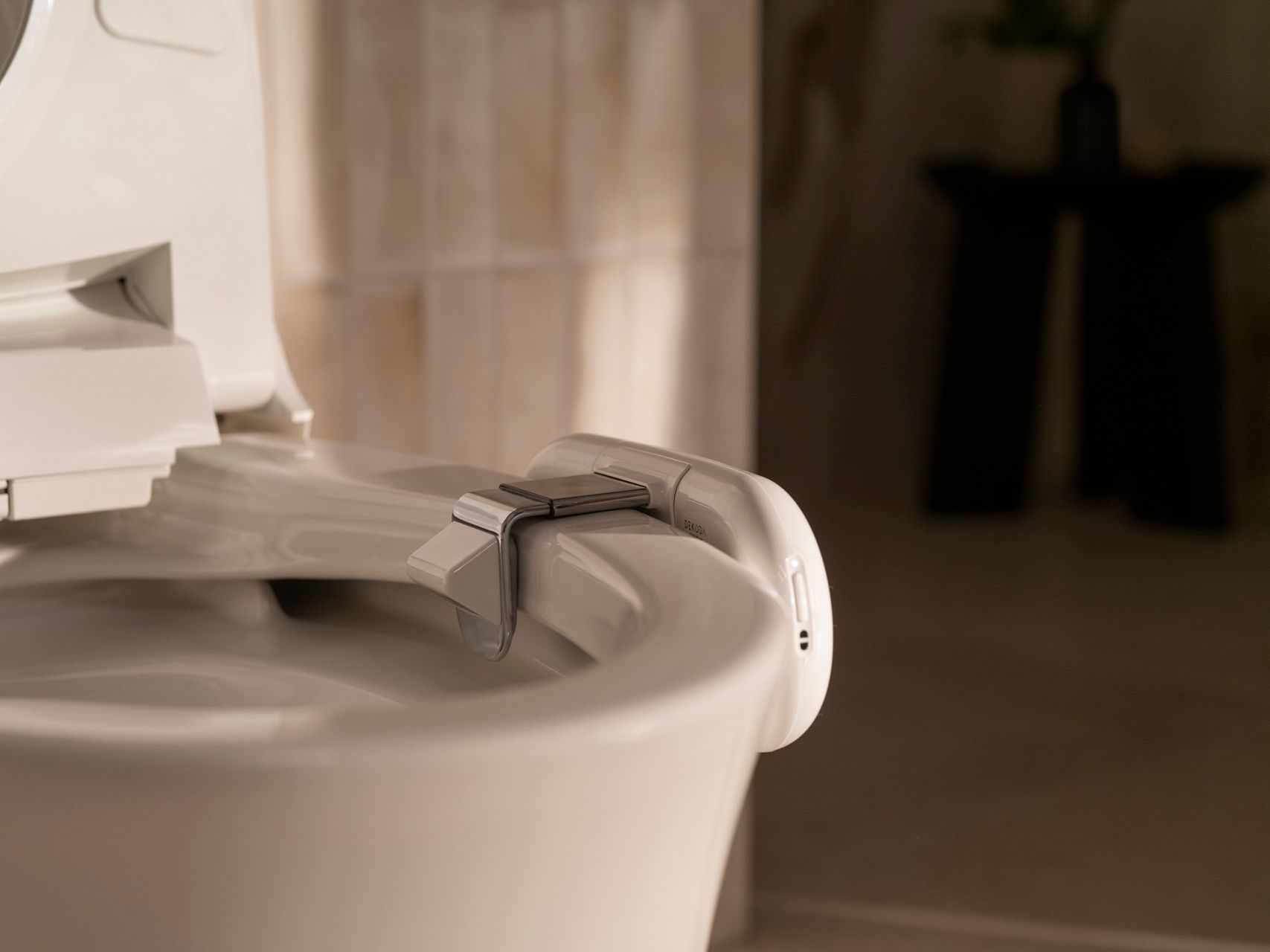 Close-up of Dekoda's adjustable mounting clamp attaching securely to the toilet rim for simple installation.