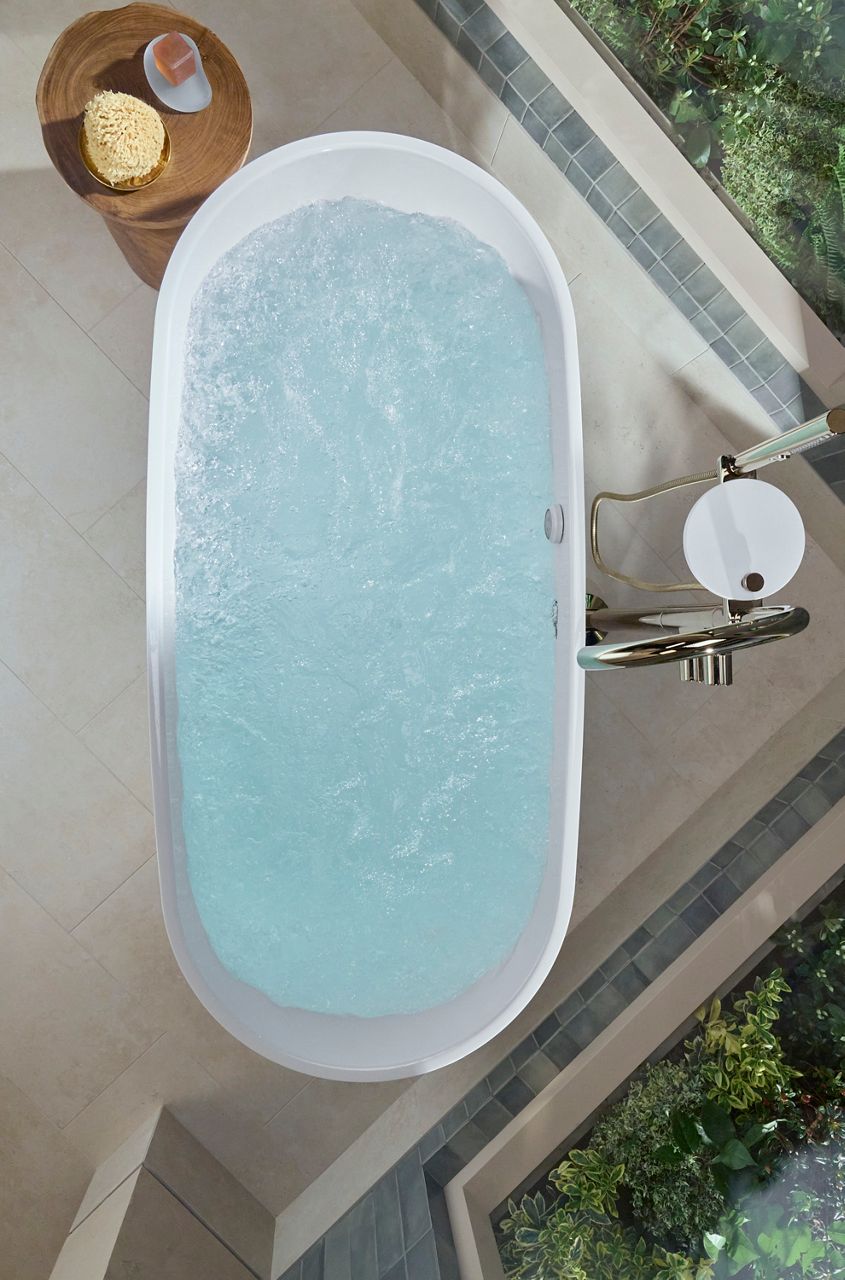 Overhead view of a freestanding oval bathtub filled with bubbling water, showcasing a relaxing hydrotherapy soaking experience.