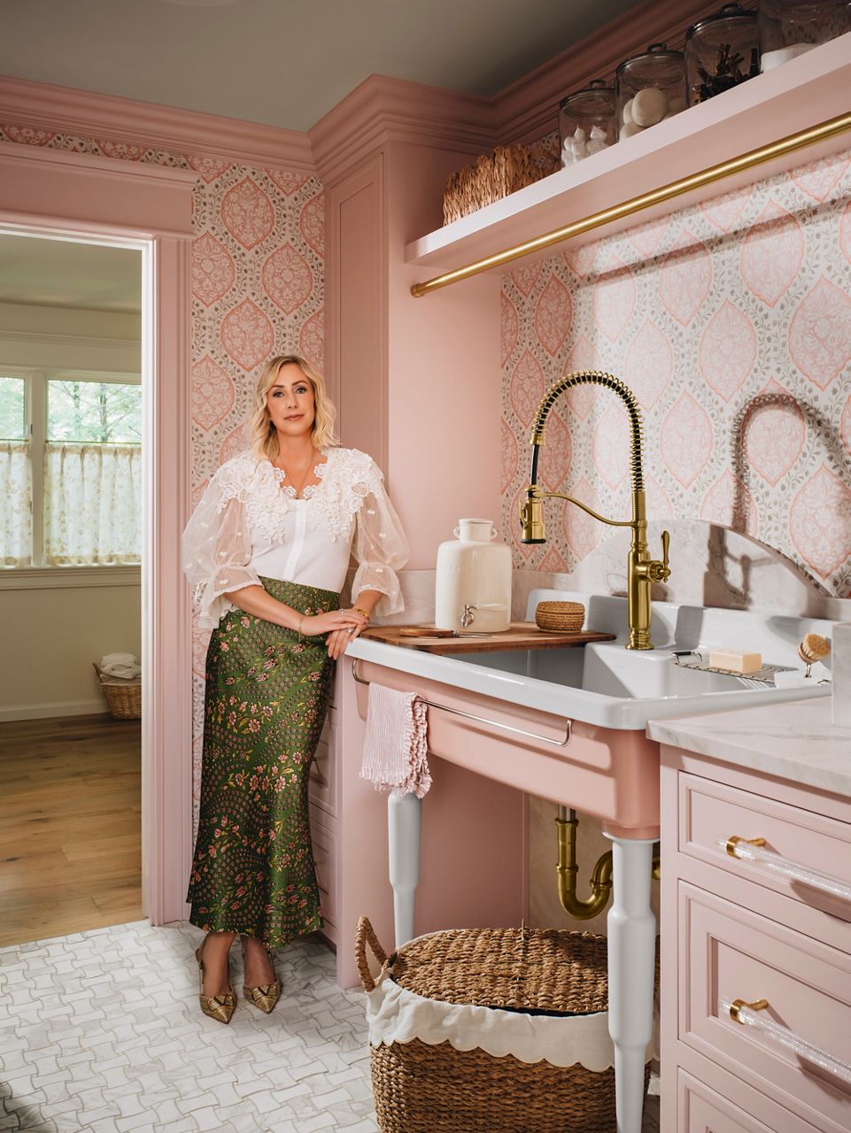 Tiffany Skilling dans une cuisine rose, appuyée contre un évier Farmstead de KOHLER.