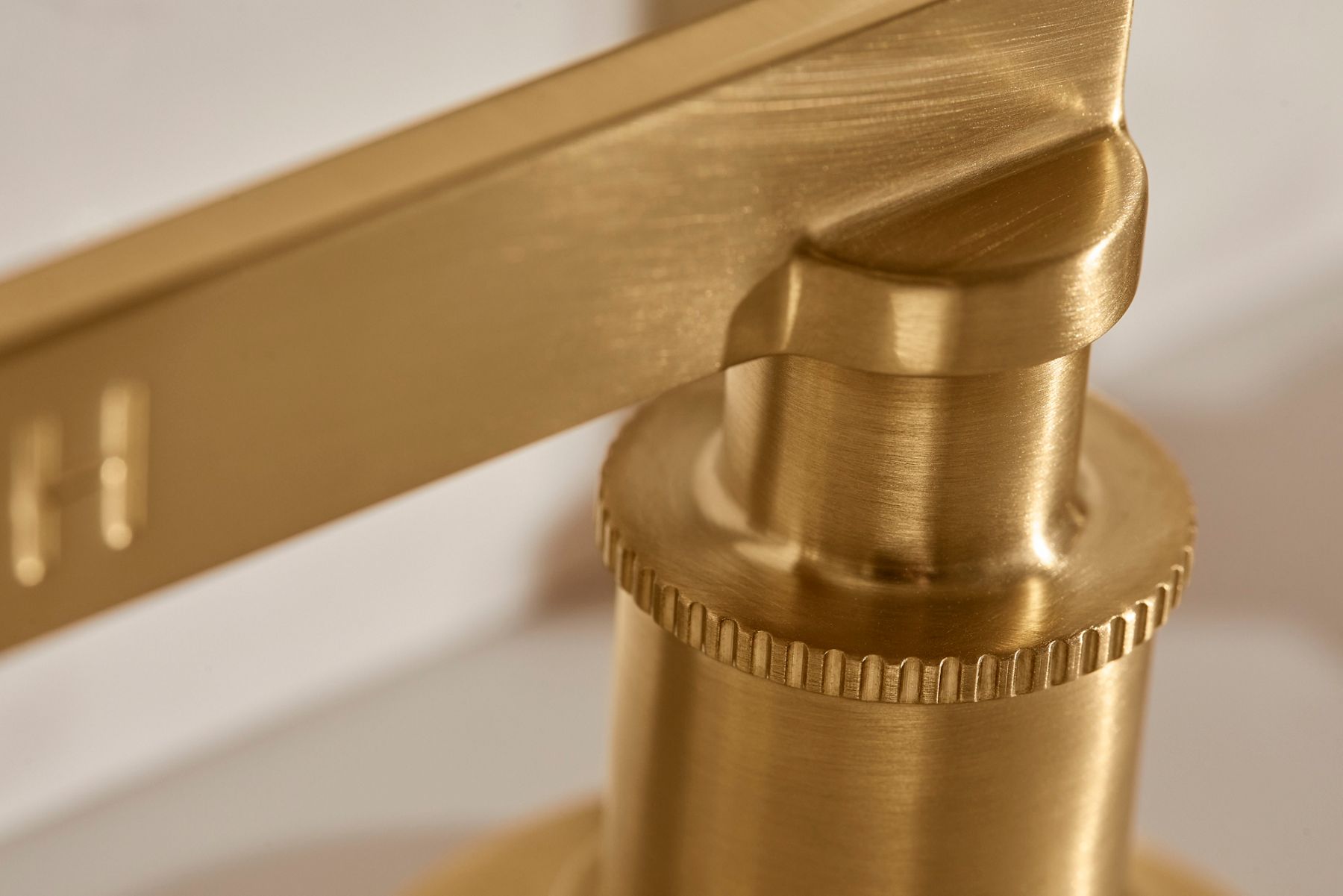 Detail of the ribbed knurling on a bathrooom faucet in brushed brass.